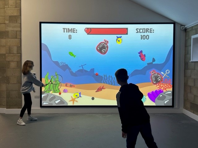 Children playing a game using the interactive gaming wall