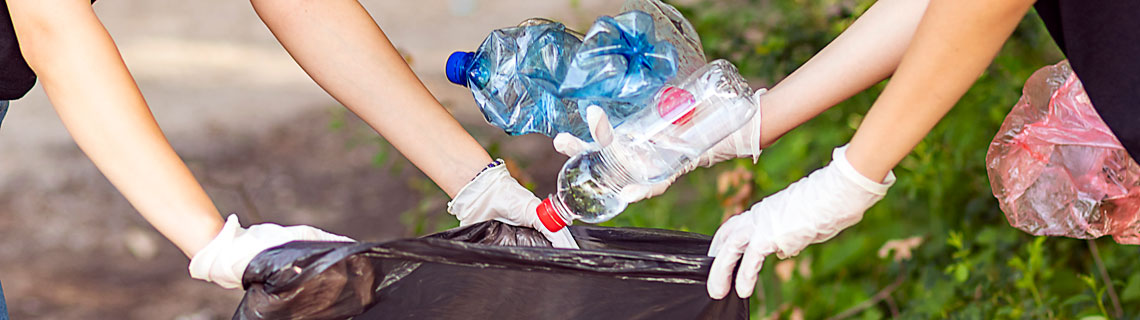 Recycling waste, hands reaching into a black bin bag 